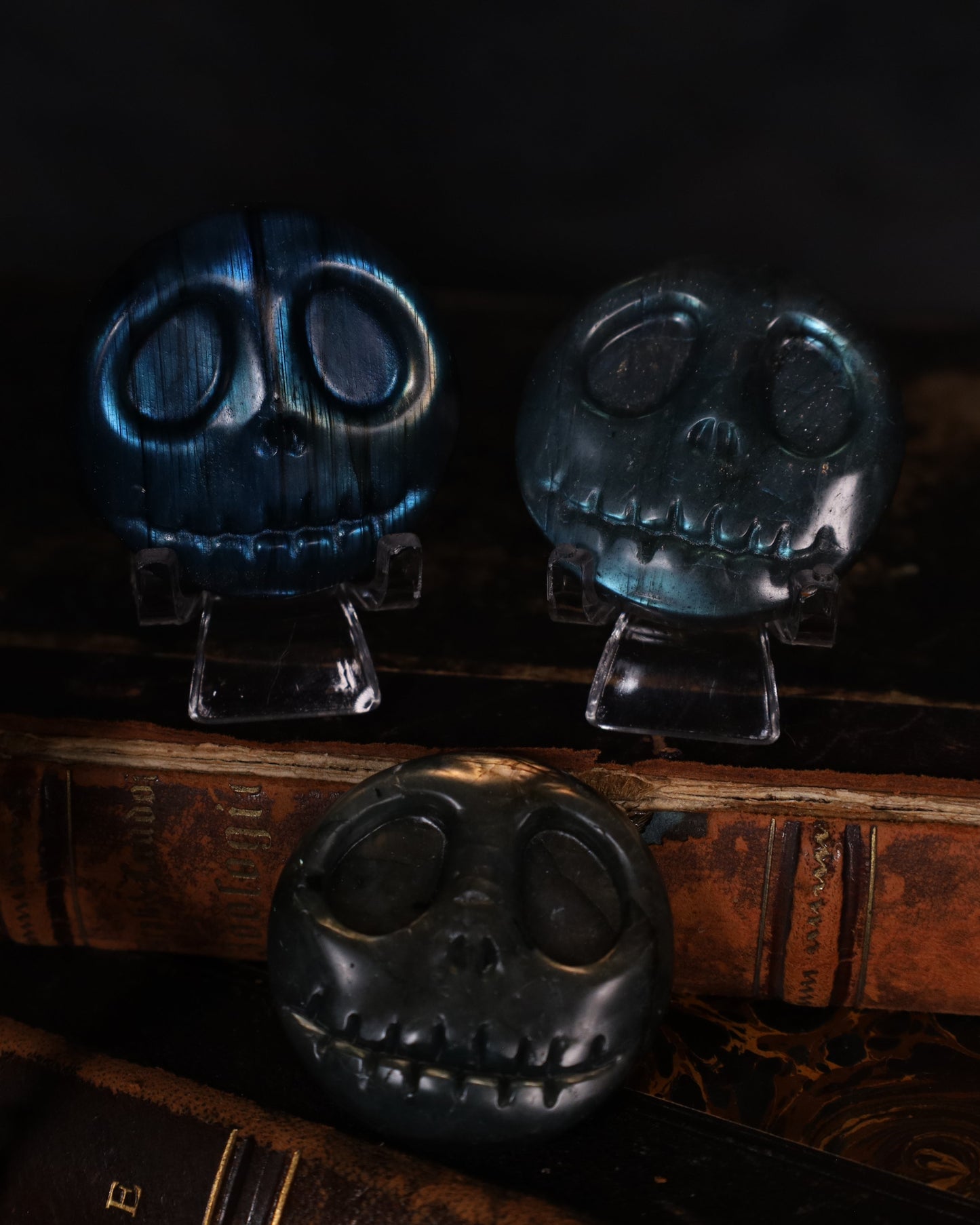 „Jack Skellington Figur aus Labradorit – handgeschnitzt, 4 cm Durchmesser, auf alten Büchern präsentiert“